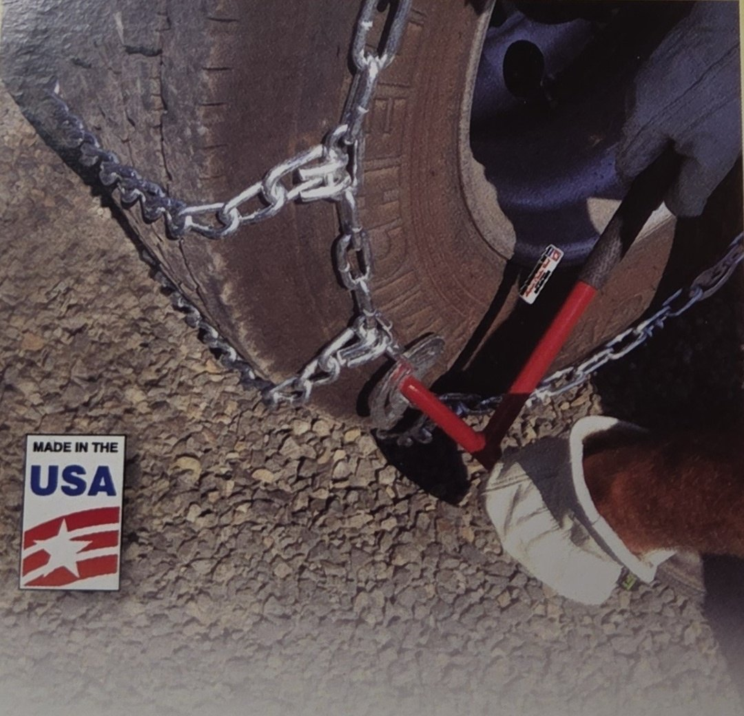 Gloved hand using a red chain tool on a cam of a tire chain on a truck tire